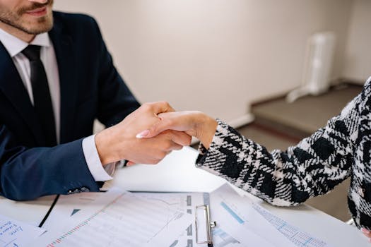 pexels photo 7693159 7693159 Close-up of a business handshake over documents in an office setting, symbolizing partnership.